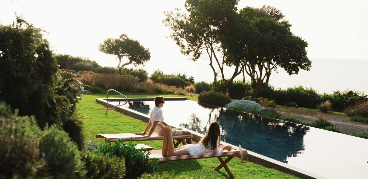 couple-sur-des-transats-pres-de-la-piscine-d-une-villa-face-a-la-mer-en-toscane
