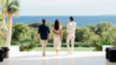 Three-adults-looking-out-to-the-garden-with-the-sea-in-the-background-in-an-luxury-villa-in-Ibiza