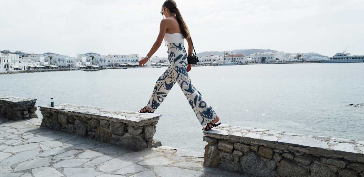 femme-marchant-au-bord-de-l-eau-vacances-luxe-grece