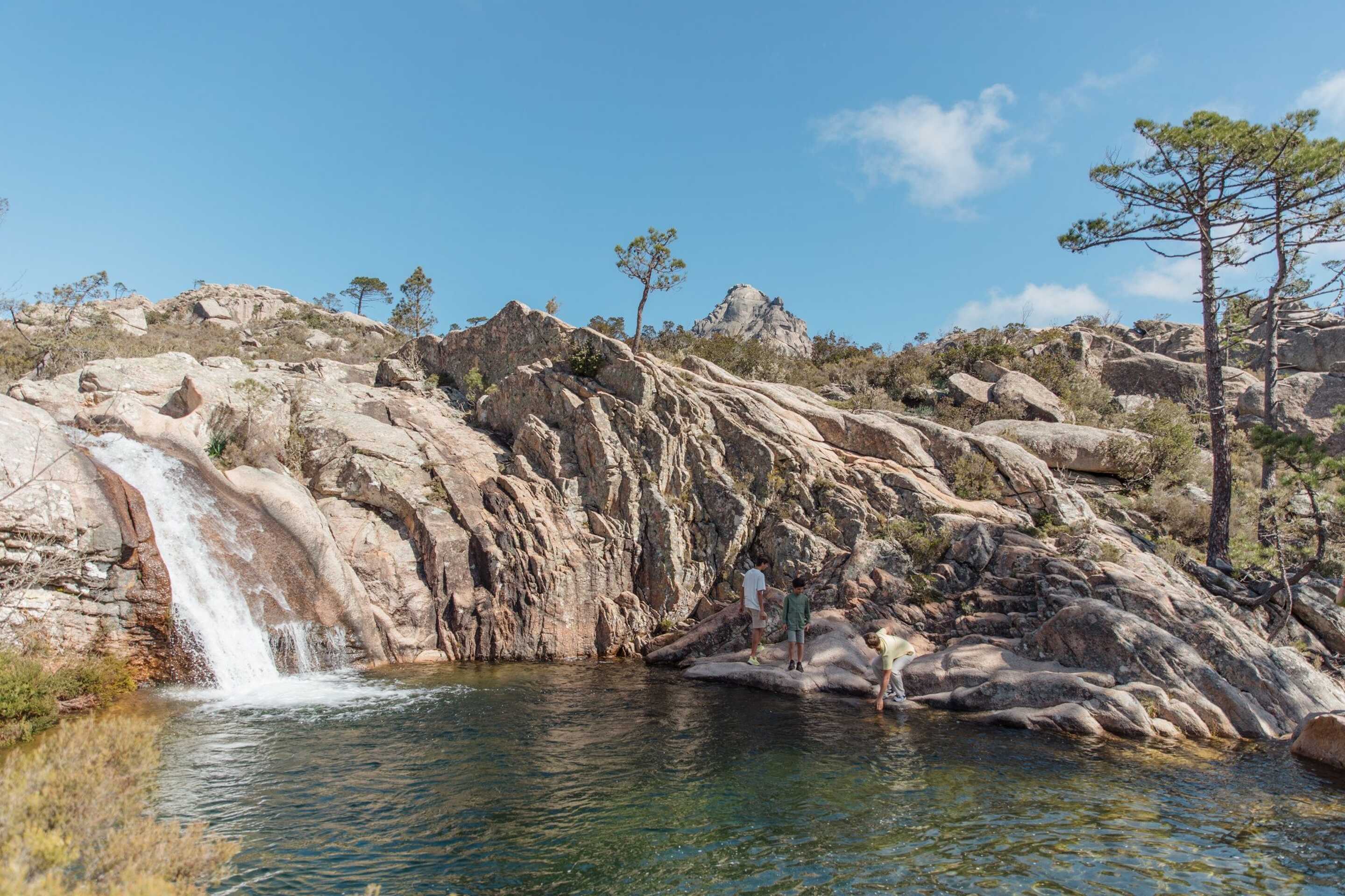 famille-avec-enfants-au-bord-d-une-cascade-dans-la-nature-en-corse-du-sud-en-ete