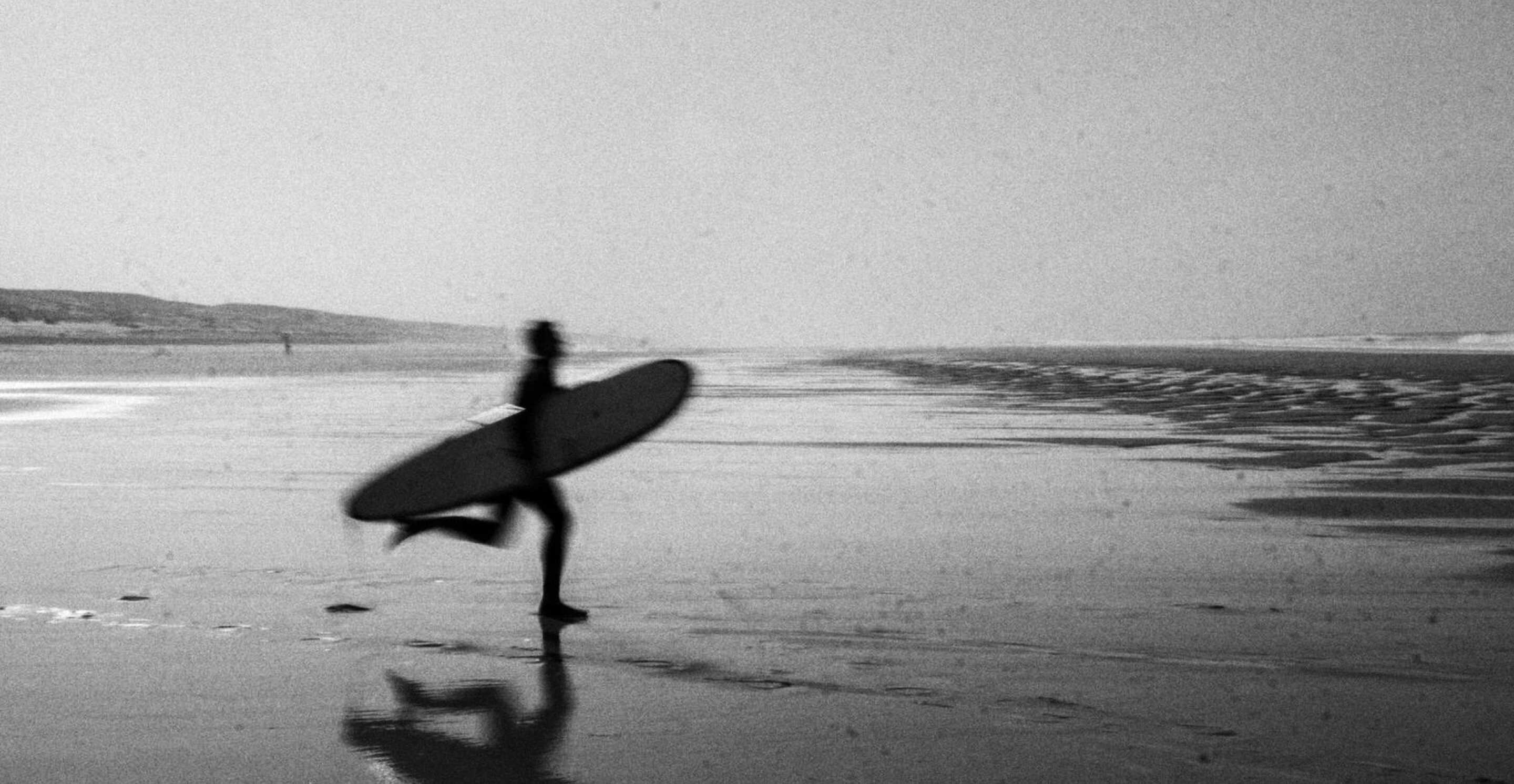 little girls on the beach sitting by a surfboard in the basque country