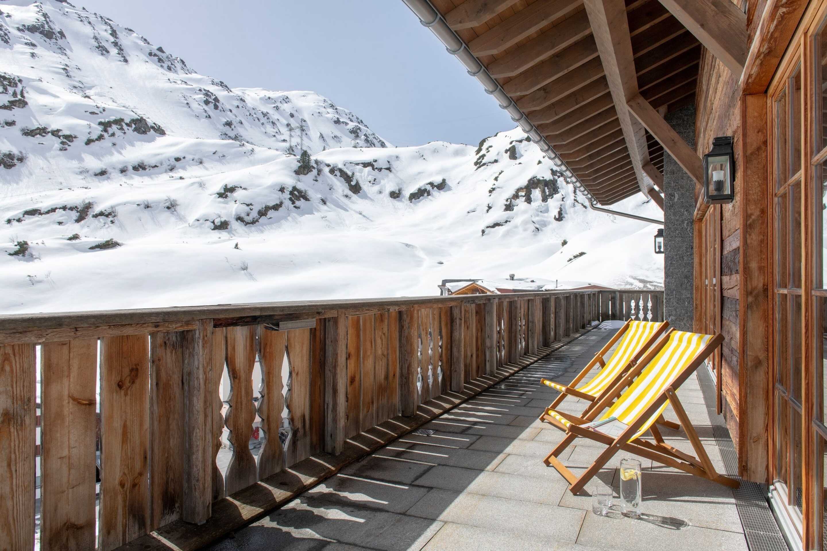 yellow wooden chairs outside chalet in the alps 
