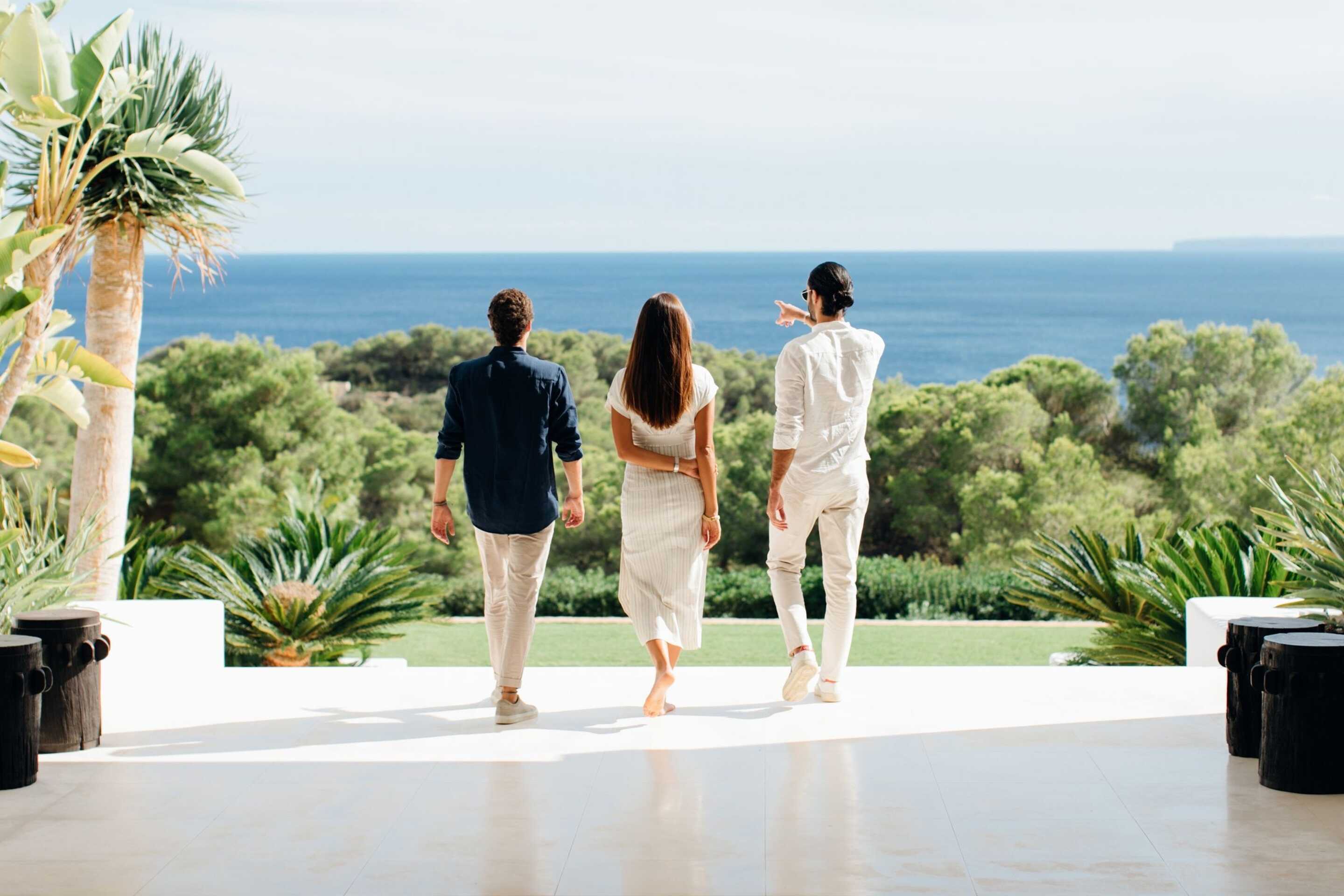 Three adults looking out to the garden with the sea in the background in a luxury villa in Ibiza