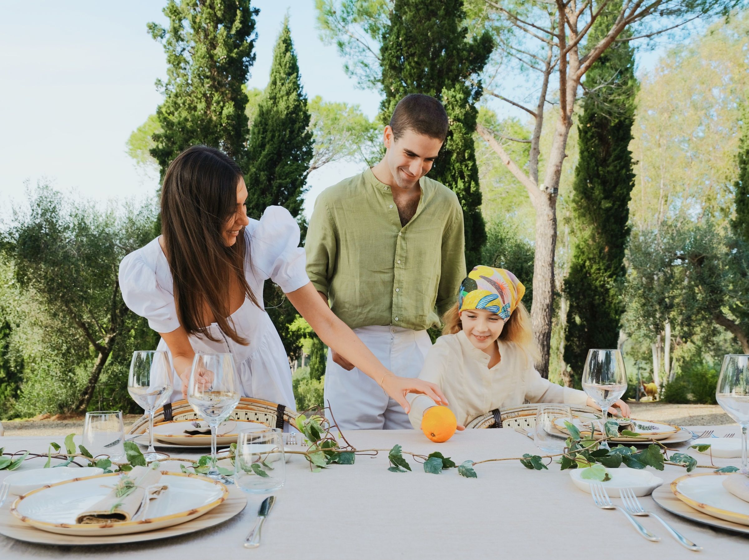 parents-avec-leur-petite-fille-dressant-la-table-dehors-campagne-italienne
