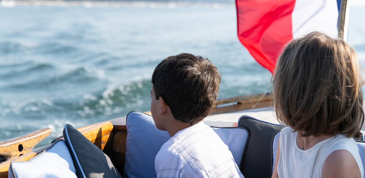 deux-enfants-assis-sur-un-bateau-avec-un-drapeau-francais-regardant-la-mer