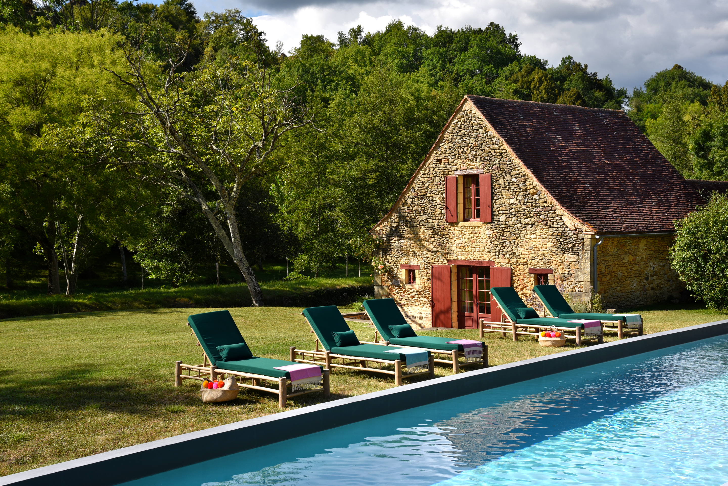 pool-house-en-pierres-dans-un-jardin-avec-une-piscine-et-cinq-transats-autour