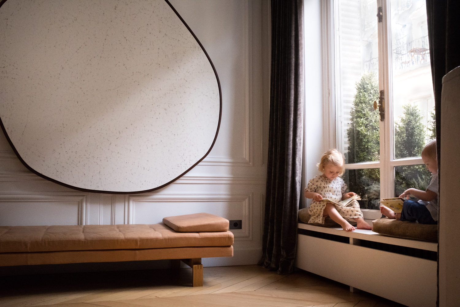 Kids in a reading nook by the window of a luxury haussmannian  flat in Paris